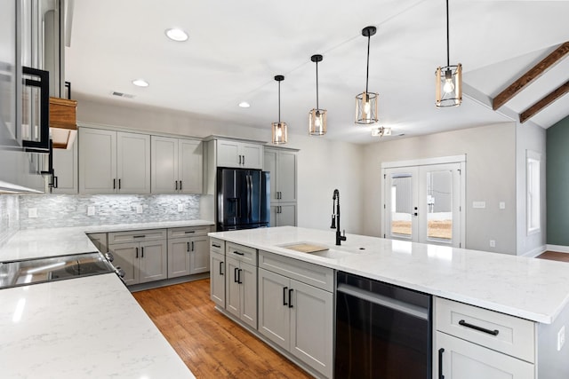 kitchen with gray cabinetry, visible vents, a sink, and black fridge with ice dispenser