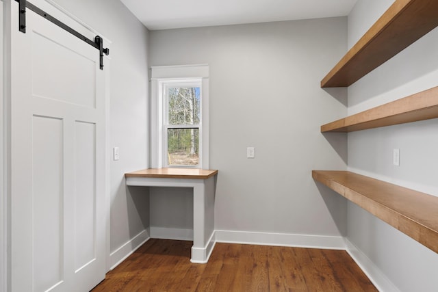 interior space featuring dark wood-type flooring, baseboards, and a barn door