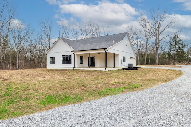 modern farmhouse style home featuring a garage, gravel driveway, central AC, and a front yard