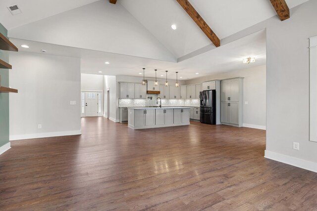 unfurnished living room featuring baseboards, visible vents, dark wood-style flooring, beamed ceiling, and high vaulted ceiling