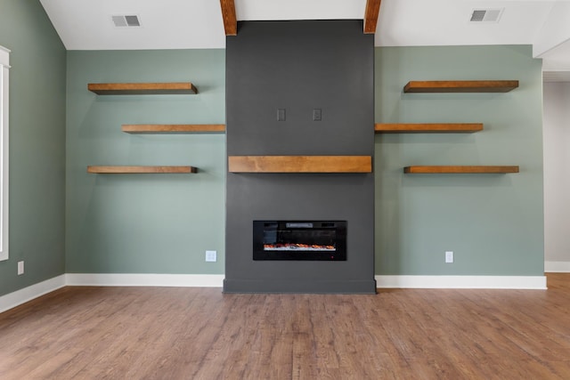 unfurnished living room with a large fireplace, wood finished floors, visible vents, and baseboards