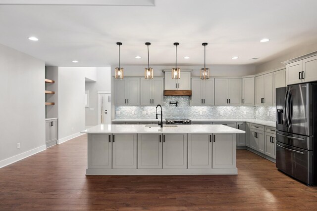 kitchen with light countertops, fridge with ice dispenser, a sink, and gray cabinetry