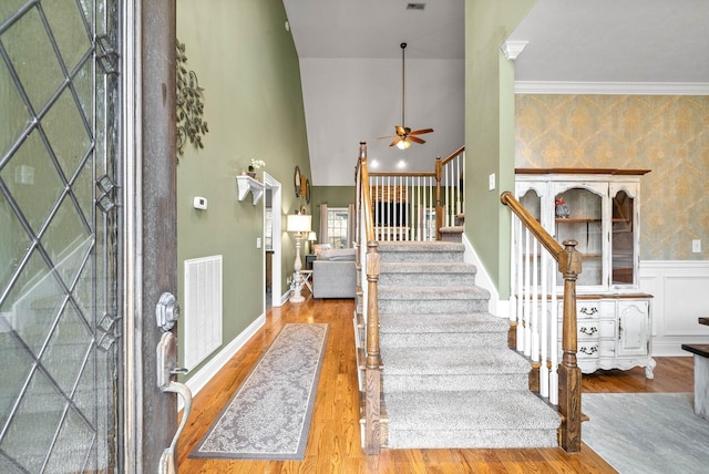 entrance foyer featuring ceiling fan, ornamental molding, light hardwood / wood-style flooring, and a high ceiling