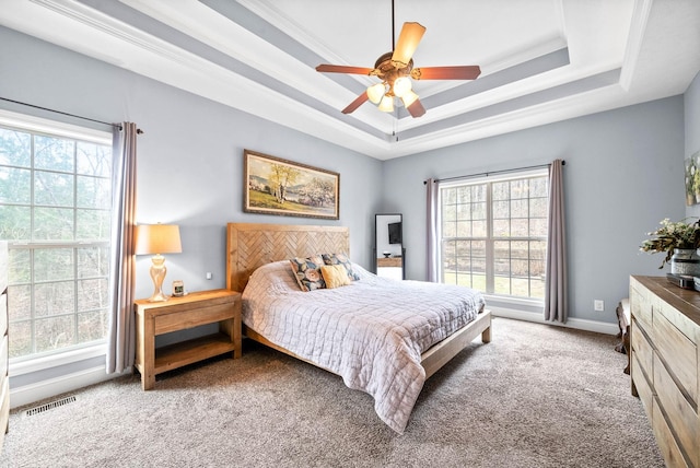 bedroom with multiple windows, crown molding, light carpet, and a tray ceiling