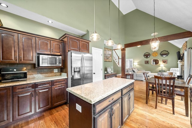 kitchen featuring hanging light fixtures, a kitchen island, wood-type flooring, and appliances with stainless steel finishes