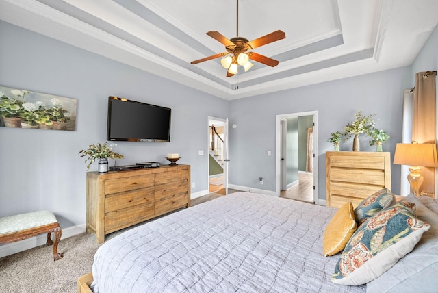 carpeted bedroom featuring ceiling fan and a tray ceiling