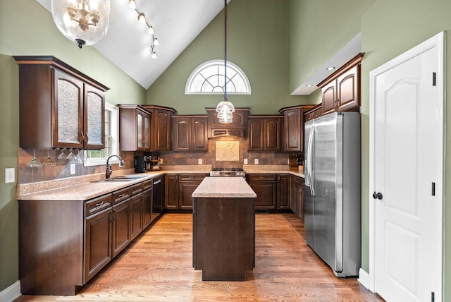 kitchen with stainless steel refrigerator with ice dispenser, dark brown cabinetry, sink, a center island, and hanging light fixtures