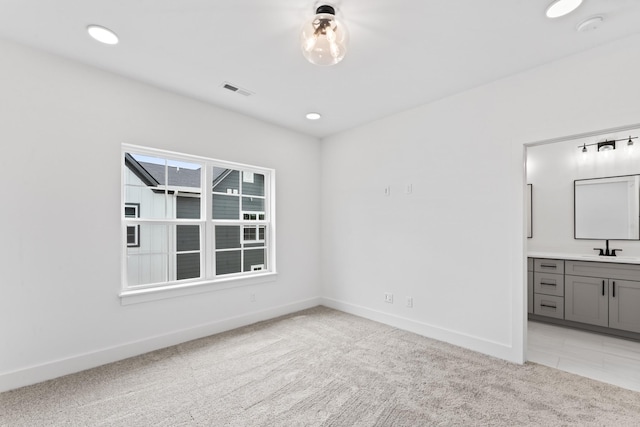 spare room featuring recessed lighting, light carpet, a sink, visible vents, and baseboards