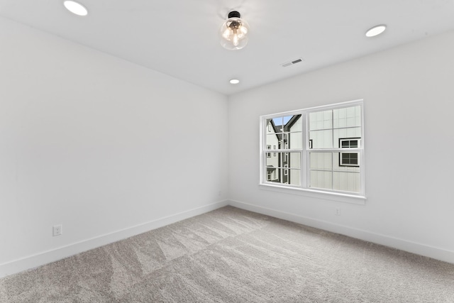 carpeted empty room with baseboards, visible vents, and recessed lighting