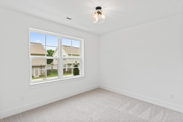 carpeted spare room with visible vents and baseboards