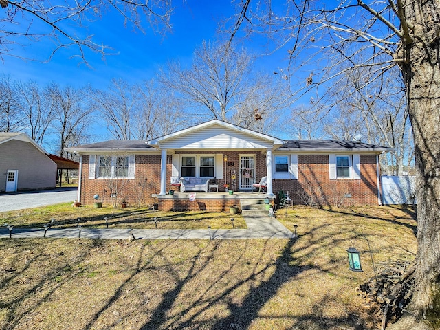 view of front of house featuring covered porch, brick siding, crawl space, and a front yard