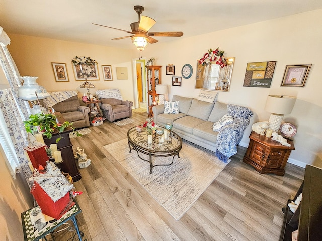 living room featuring ceiling fan, baseboards, and wood finished floors