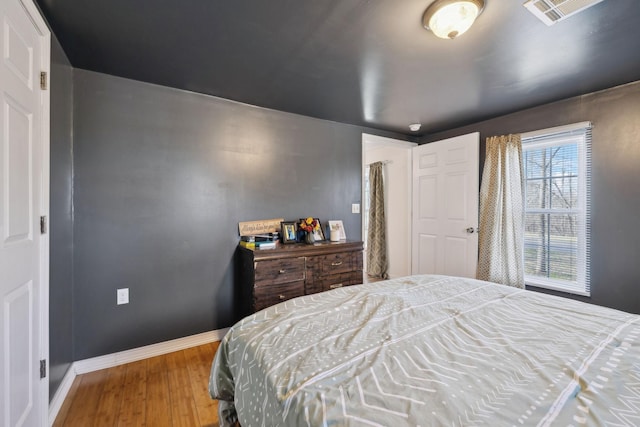 bedroom with visible vents, baseboards, and wood finished floors