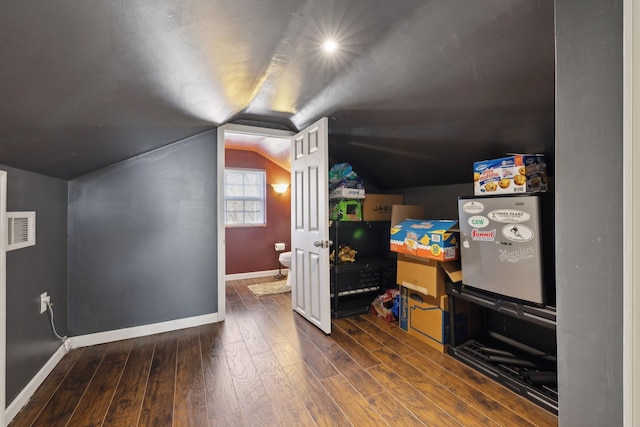 additional living space featuring wood-type flooring, visible vents, vaulted ceiling, and baseboards