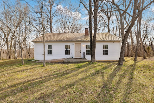 single story home with a front yard, metal roof, and a chimney