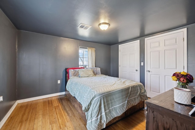 bedroom featuring wood finished floors, visible vents, and baseboards