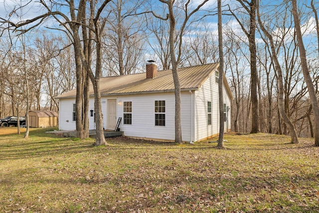 view of front of house with an outbuilding, metal roof, a shed, a chimney, and a front yard