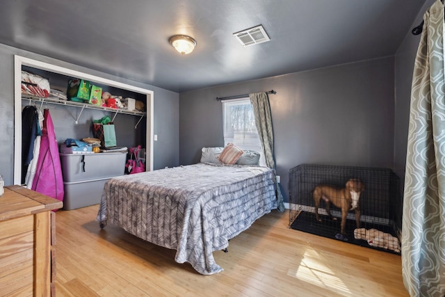 bedroom with a closet, visible vents, and wood finished floors