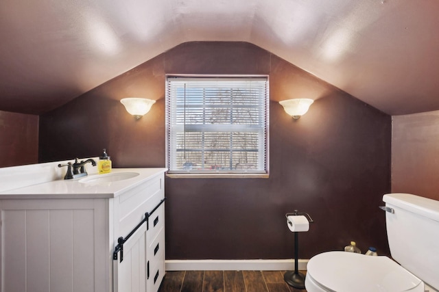 half bathroom featuring baseboards, toilet, lofted ceiling, wood finished floors, and vanity