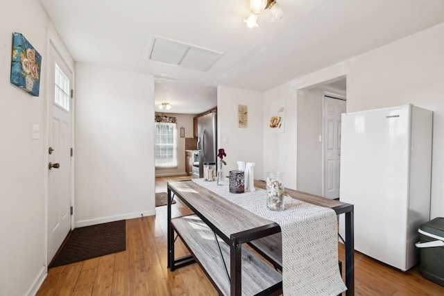 dining space with light wood-type flooring, visible vents, and a wealth of natural light