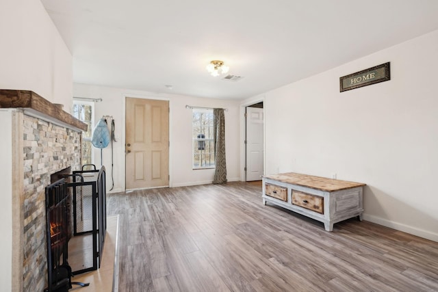 interior space featuring light wood-type flooring, visible vents, a fireplace, and baseboards