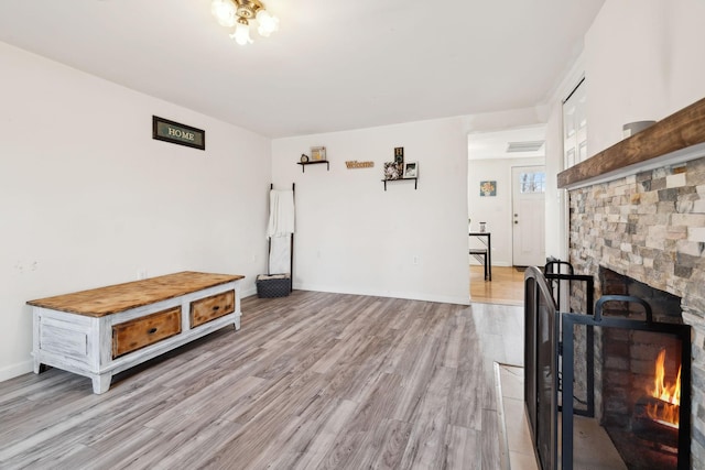 living area featuring visible vents, a fireplace, light wood-style flooring, and baseboards