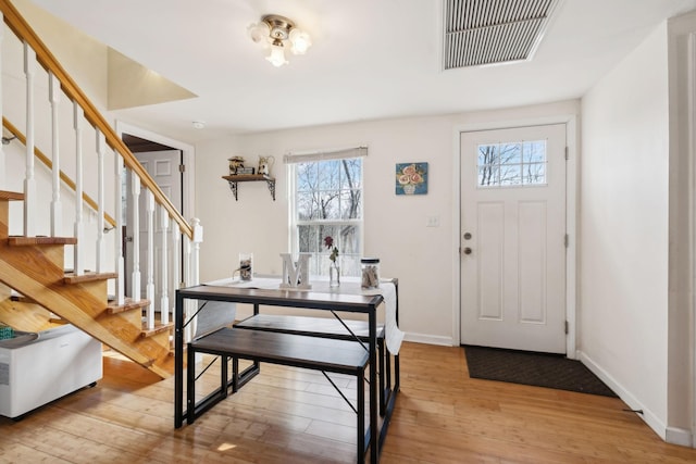 entryway with hardwood / wood-style flooring, baseboards, stairs, and visible vents