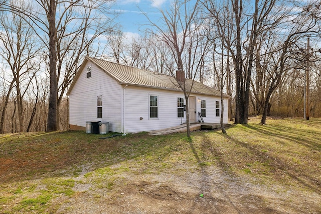 view of front of house with metal roof, a chimney, and a front yard