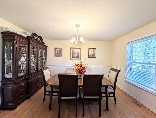 dining room with light hardwood / wood-style floors and a chandelier