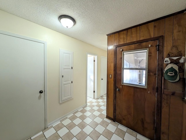 foyer with wood walls and a textured ceiling