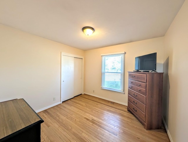 bedroom with light hardwood / wood-style floors and a closet