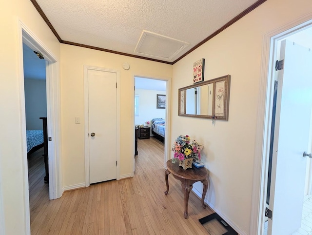 corridor featuring a textured ceiling, crown molding, and light hardwood / wood-style flooring