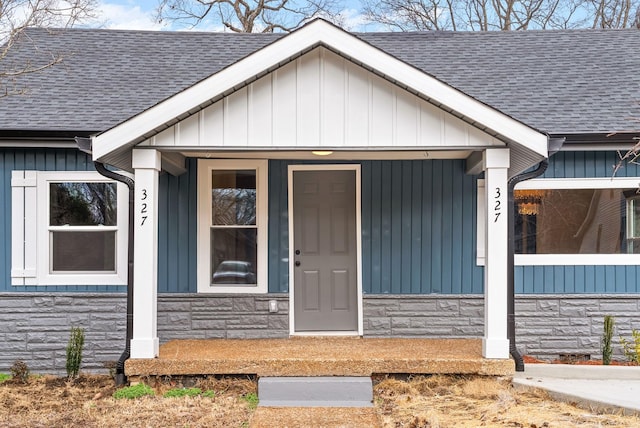 property entrance featuring stone siding, a porch, board and batten siding, and roof with shingles