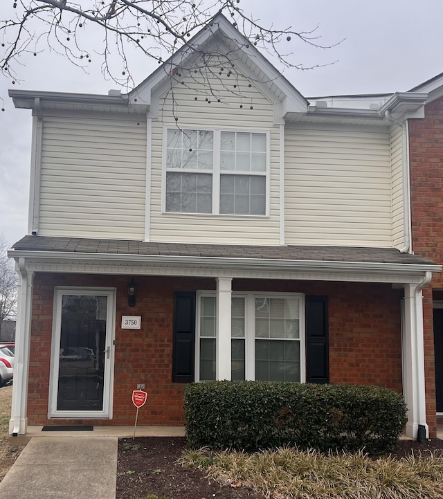 view of front of home featuring brick siding and a shingled roof