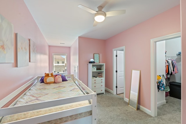 carpeted bedroom with ceiling fan, a walk in closet, and a closet