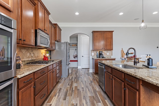 kitchen with sink, stainless steel appliances, crown molding, and hanging light fixtures