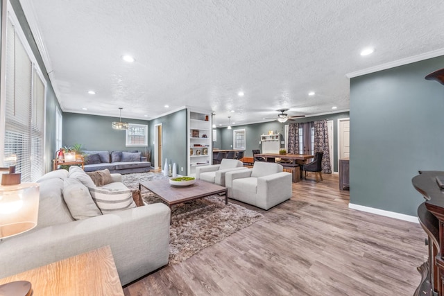 living room featuring crown molding, hardwood / wood-style flooring, ceiling fan with notable chandelier, and a textured ceiling