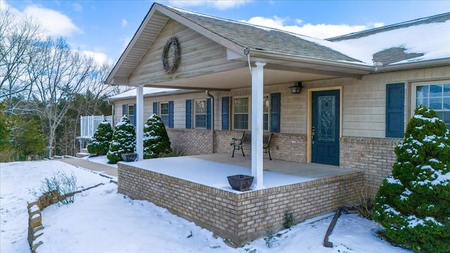 view of front of property featuring covered porch, roof with shingles, and brick siding