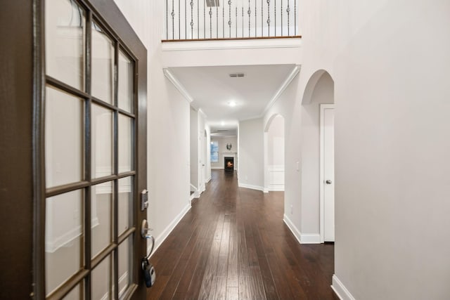 hall with ornamental molding, a towering ceiling, and dark hardwood / wood-style floors