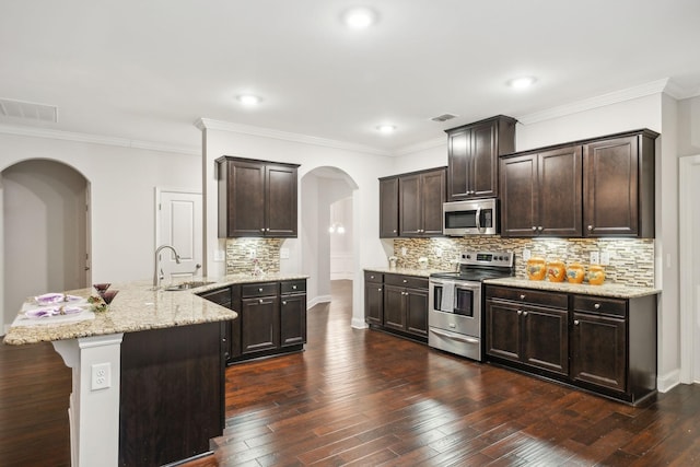 kitchen with stainless steel appliances, dark brown cabinetry, a center island, sink, and dark hardwood / wood-style floors