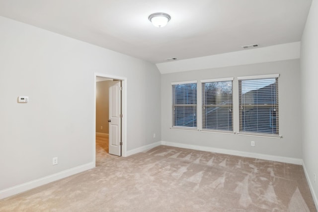 empty room with light colored carpet and lofted ceiling