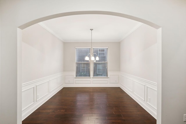 unfurnished dining area featuring ornamental molding, an inviting chandelier, and wood-type flooring