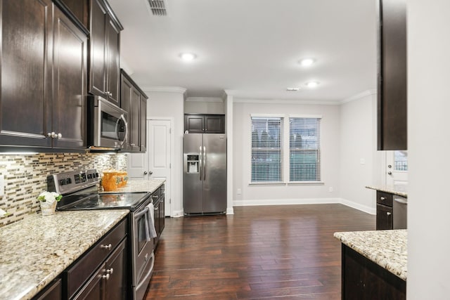 kitchen with light stone counters, stainless steel appliances, dark brown cabinets, ornamental molding, and tasteful backsplash