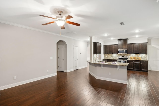 kitchen with dark wood-type flooring, tasteful backsplash, light stone countertops, and stainless steel appliances