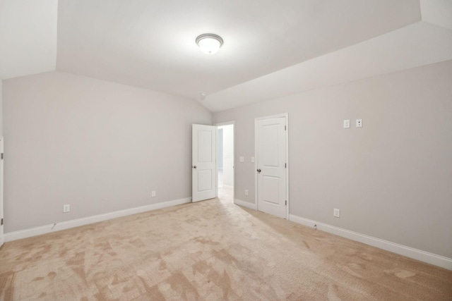 empty room featuring vaulted ceiling and light colored carpet