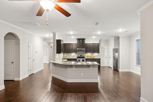 kitchen with appliances with stainless steel finishes, tasteful backsplash, light stone counters, a breakfast bar, and kitchen peninsula