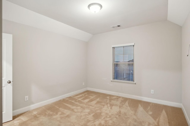 carpeted empty room with vaulted ceiling