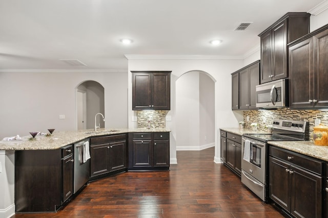 kitchen with sink, dark hardwood / wood-style floors, stainless steel appliances, dark brown cabinets, and decorative backsplash