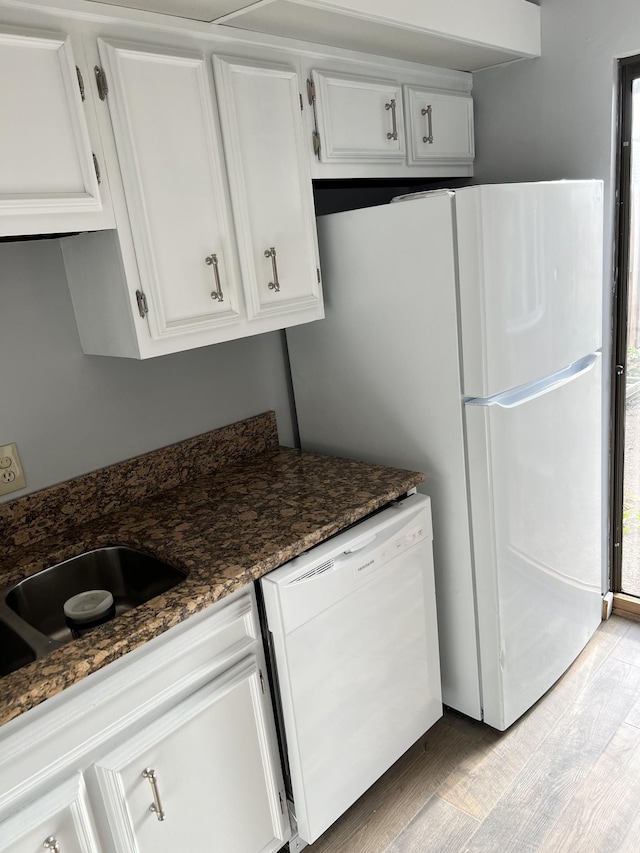 kitchen featuring white cabinets, light hardwood / wood-style flooring, dark stone counters, and dishwasher