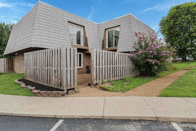 214 Cedarwood Ln Unit 214, Madison, TN 37115 - view of side of property featuring brick siding, mansard roof, a balcony, and uncovered parking